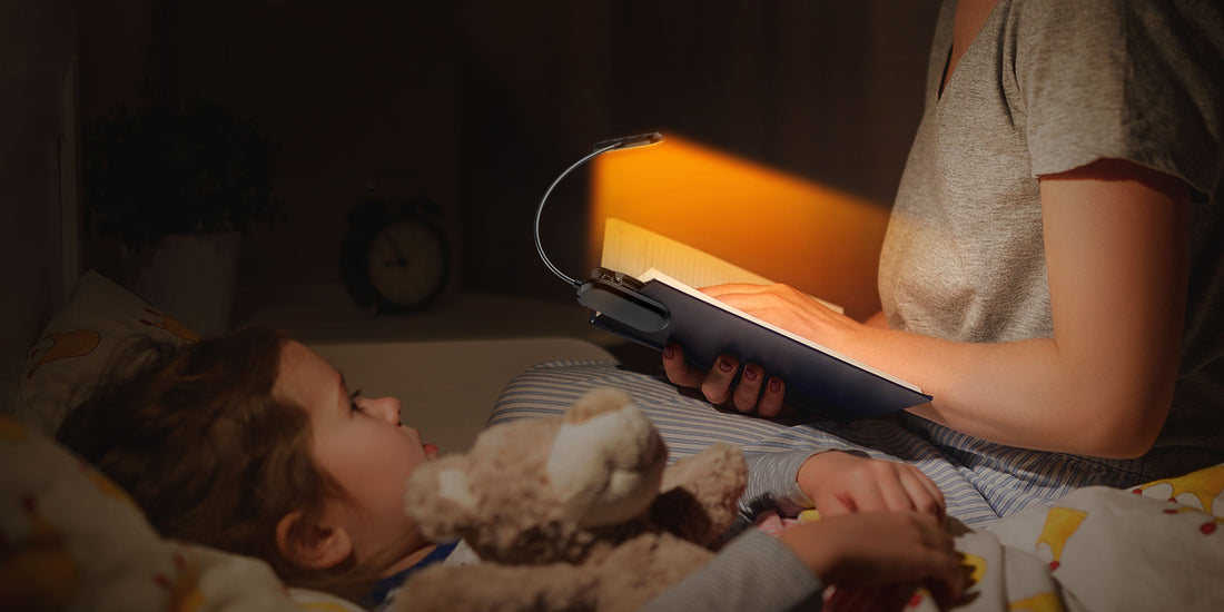 Mother and child reading a bedtime story illuminated by an amber LED clip-on book light to protect sleep.